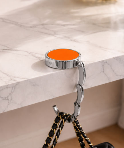 Oranje opvouwbare tassenhanger aan tafel met handtas