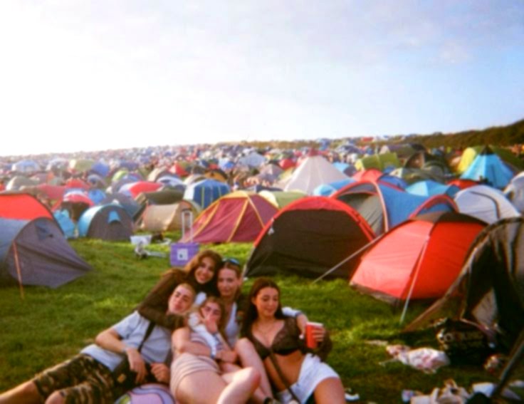 Eine Gruppe von Freunden vor ihren Zelten auf dem Festival-Campingplatz